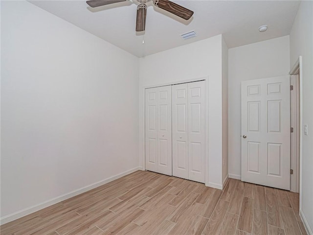 unfurnished bedroom featuring baseboards, visible vents, light wood finished floors, ceiling fan, and a closet