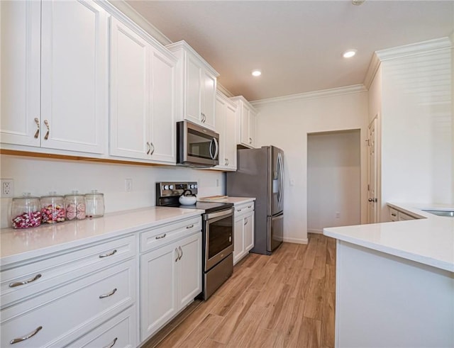 kitchen with ornamental molding, white cabinetry, appliances with stainless steel finishes, light wood finished floors, and light countertops