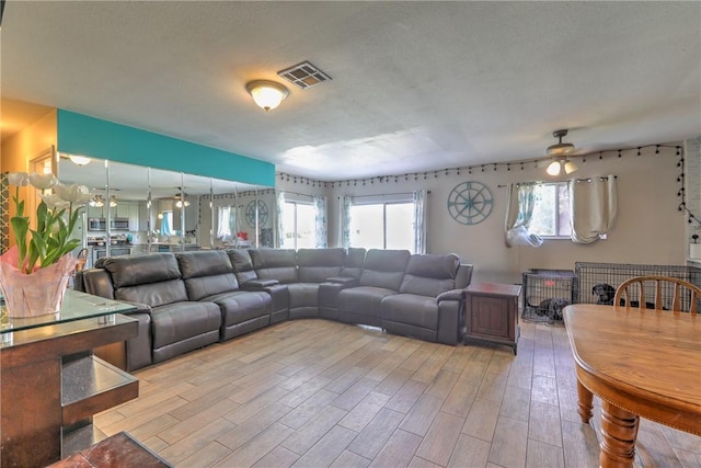 living area with a textured ceiling, light wood-type flooring, and visible vents