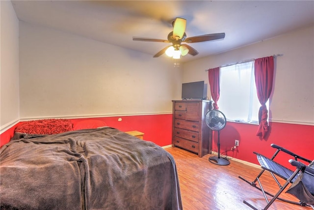 bedroom featuring light wood finished floors, baseboards, and a ceiling fan