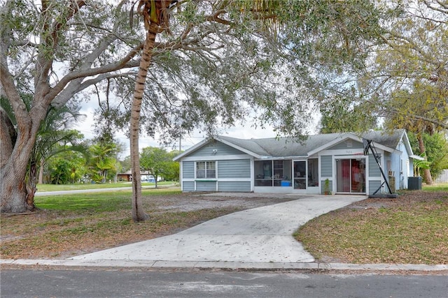 ranch-style home with concrete driveway, a front lawn, and central air condition unit