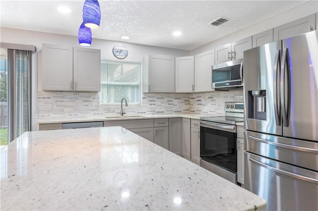 kitchen featuring stainless steel appliances, hanging light fixtures, sink, and gray cabinetry