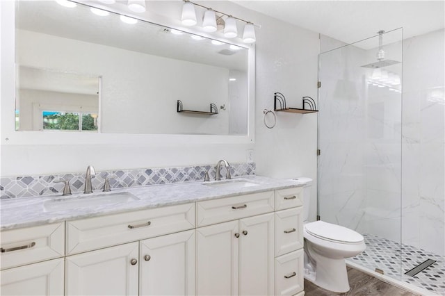 bathroom with hardwood / wood-style flooring, vanity, tiled shower, and toilet