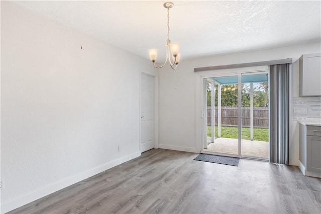 unfurnished dining area with a chandelier and light wood-type flooring