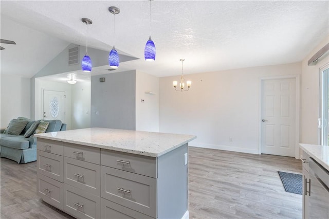 kitchen featuring a kitchen island, stainless steel dishwasher, light hardwood / wood-style flooring, and decorative light fixtures