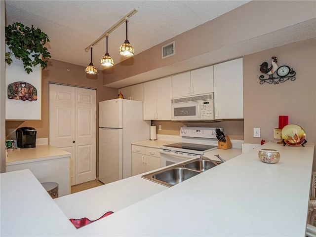 kitchen featuring white appliances, sink, white cabinets, kitchen peninsula, and pendant lighting