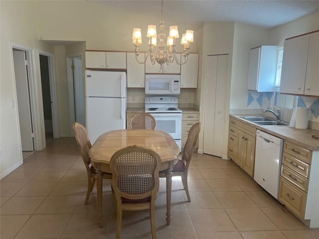 kitchen with white appliances, a chandelier, light tile patterned floors, pendant lighting, and sink