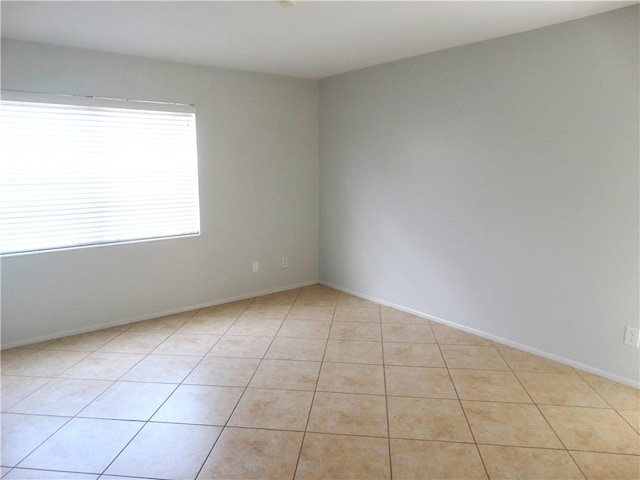 spare room with light tile patterned flooring and baseboards
