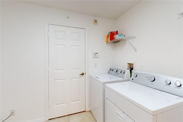 clothes washing area with washing machine and dryer, laundry area, and light tile patterned floors