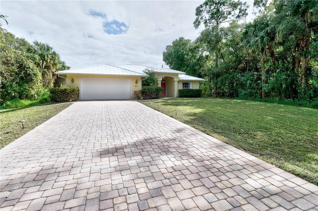 single story home featuring decorative driveway, stucco siding, a front yard, metal roof, and a garage