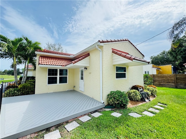 back of property featuring a lawn and a deck