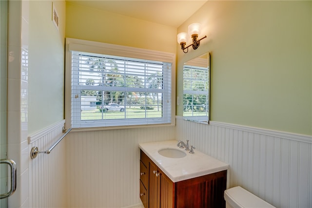 bathroom featuring vanity, a shower with shower door, and toilet