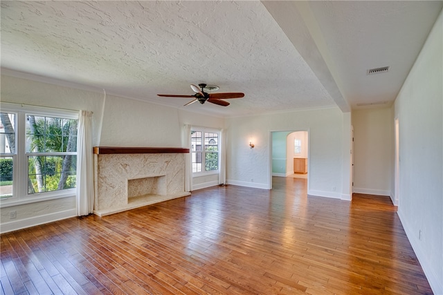 unfurnished living room featuring a textured ceiling, ceiling fan, crown molding, wood-type flooring, and a fireplace