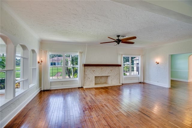 unfurnished living room featuring ornamental molding, hardwood / wood-style flooring, ceiling fan, and a healthy amount of sunlight