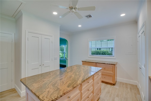 kitchen featuring light stone countertops, light brown cabinetry, light wood-type flooring, ceiling fan, and a center island