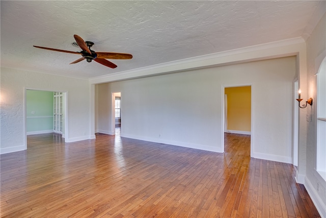 empty room featuring wood-type flooring, a textured ceiling, ceiling fan, and crown molding