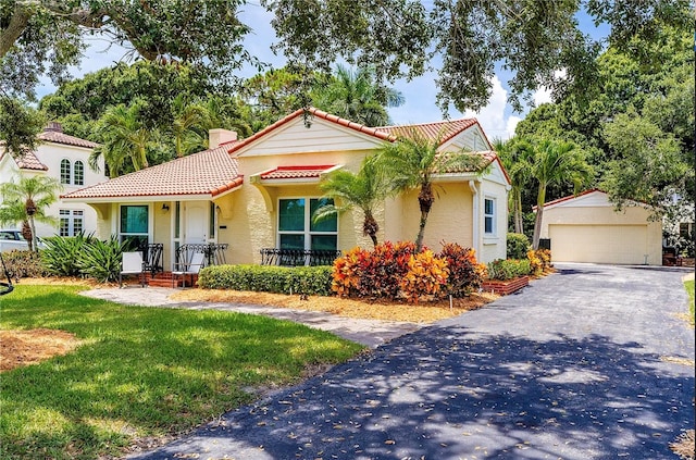 mediterranean / spanish-style home with a front yard, an outdoor structure, and a garage