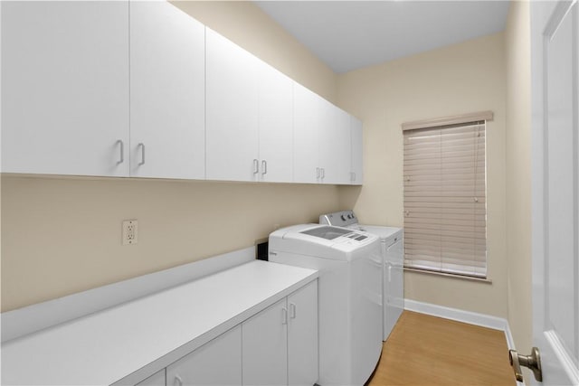 laundry room featuring washer and clothes dryer, cabinets, and light hardwood / wood-style flooring