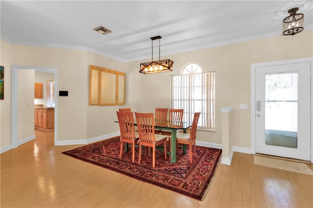 dining space featuring crown molding, a healthy amount of sunlight, and light hardwood / wood-style flooring