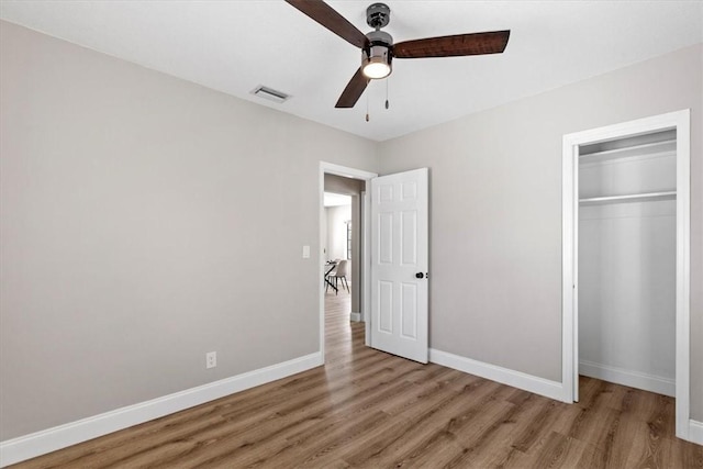 unfurnished bedroom with ceiling fan, wood-type flooring, and a closet