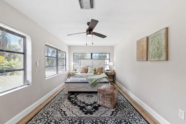 bedroom featuring hardwood / wood-style flooring, ceiling fan, and multiple windows