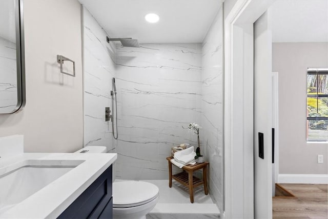 bathroom featuring vanity, hardwood / wood-style flooring, toilet, and a tile shower