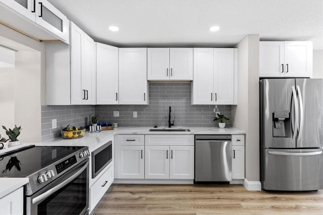 kitchen featuring white cabinetry, appliances with stainless steel finishes, light stone countertops, and sink