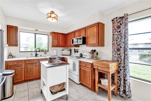 426 12th St SW, Vero Beach, FL 32962 - kitchen featuring white range with electric stovetop, stainless steel microwave, a sink, and brown cabinets