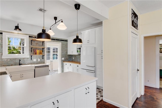 kitchen with sink, hanging light fixtures, dishwashing machine, white fridge, and white cabinets