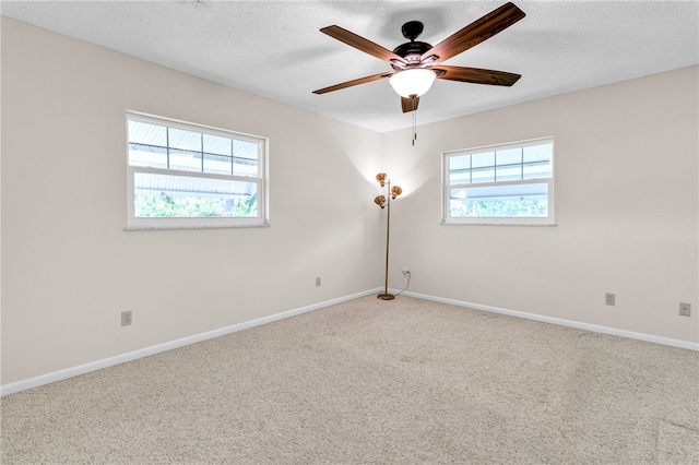 carpeted spare room with a wealth of natural light, ceiling fan, and a textured ceiling