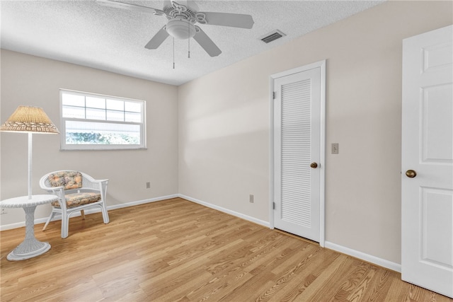 sitting room featuring a textured ceiling, light hardwood / wood-style floors, and ceiling fan