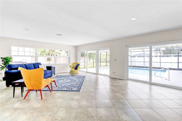 living room featuring a wealth of natural light, a textured ceiling, and light tile patterned floors