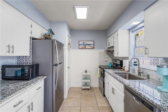 kitchen with under cabinet range hood, white cabinets, appliances with stainless steel finishes, and a sink