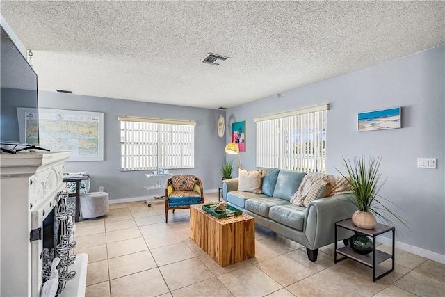 living room with a wealth of natural light, a textured ceiling, visible vents, and light tile patterned floors