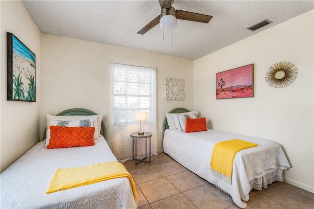 bedroom featuring tile patterned floors, a ceiling fan, visible vents, and a textured ceiling