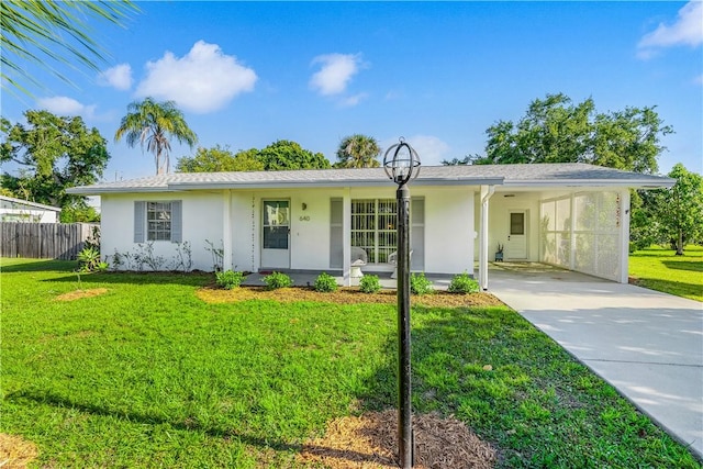 ranch-style home featuring a front lawn, driveway, a carport, fence, and stucco siding