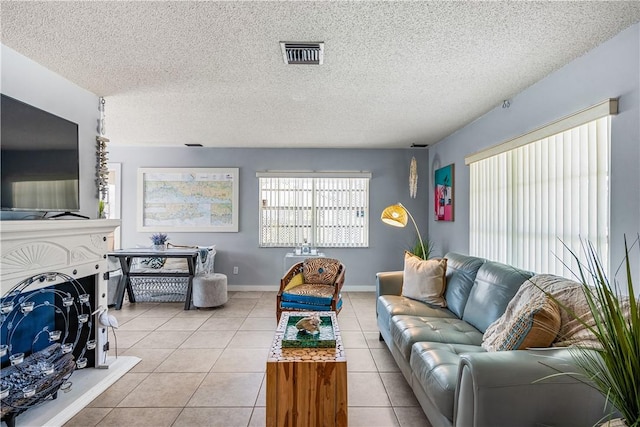 living area featuring tile patterned floors, visible vents, and a textured ceiling