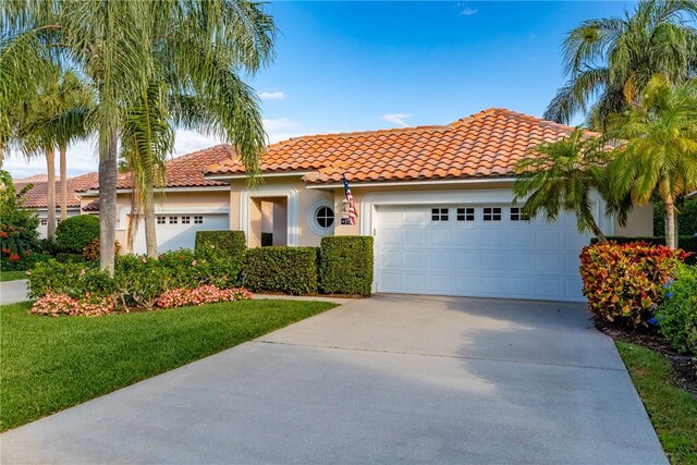1725 Victoria Cir, Vero Beach, FL 32967 - mediterranean / spanish house with a tiled roof, concrete driveway, a front yard, stucco siding, and an attached garage