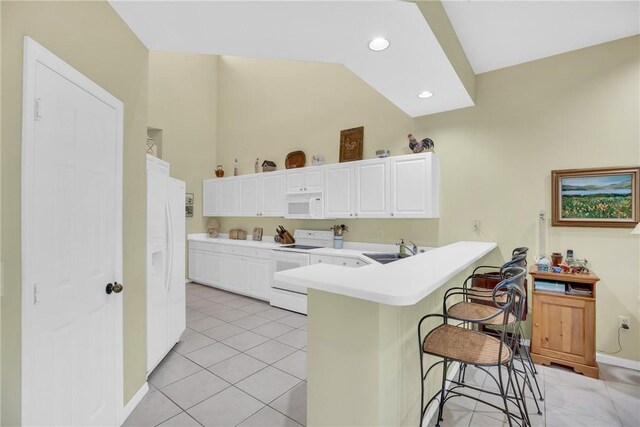 1725 Victoria Cir, Vero Beach, FL 32967 - kitchen with a breakfast bar, a peninsula, white appliances, white cabinetry, and a sink