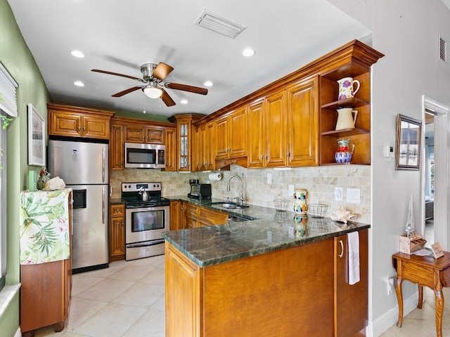 kitchen featuring sink, decorative backsplash, dark stone countertops, kitchen peninsula, and stainless steel appliances