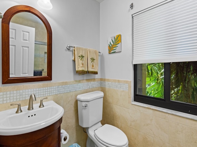 bathroom featuring vanity, toilet, and tile walls