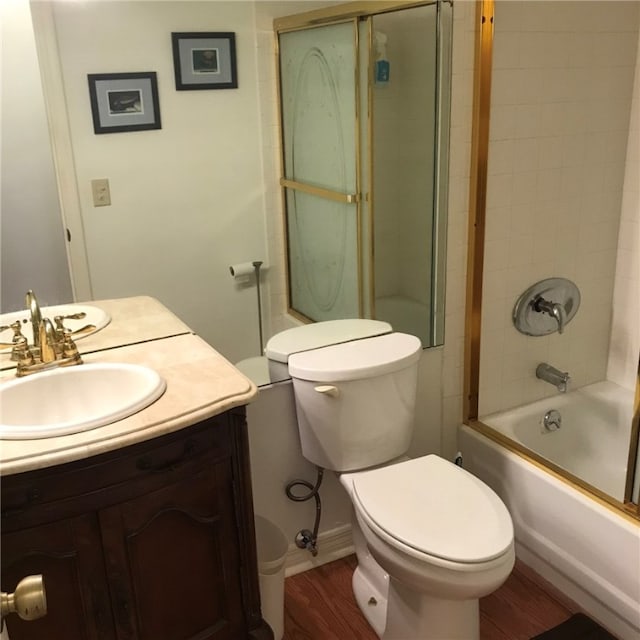 full bathroom with hardwood / wood-style flooring, vanity, combined bath / shower with glass door, and toilet