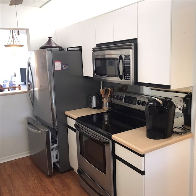 kitchen with dark wood-type flooring, white cabinets, hanging light fixtures, and stainless steel appliances