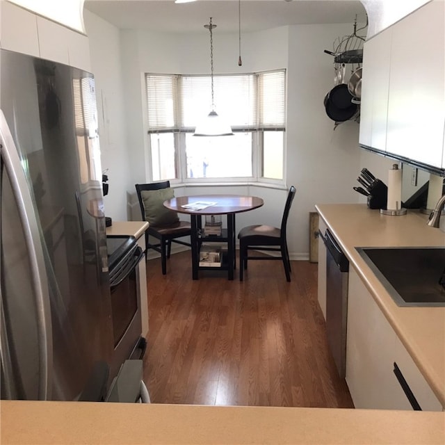 kitchen featuring white cabinetry, appliances with stainless steel finishes, decorative light fixtures, and dark hardwood / wood-style floors