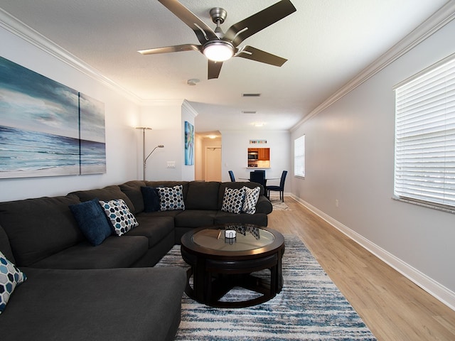 living room with ceiling fan, wood finished floors, visible vents, baseboards, and crown molding