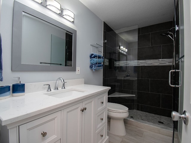 bathroom featuring a textured ceiling, vanity, a shower stall, and toilet