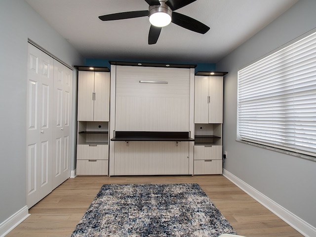 interior space featuring light wood-type flooring, a ceiling fan, and baseboards