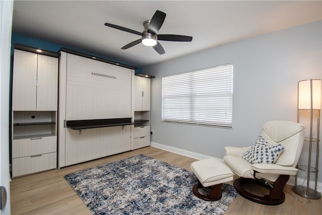 sitting room with baseboards, ceiling fan, and light wood finished floors