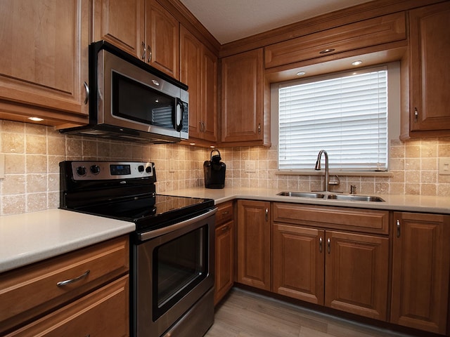 kitchen featuring brown cabinets, appliances with stainless steel finishes, light countertops, and a sink