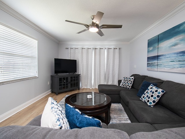 living room featuring ornamental molding, a ceiling fan, baseboards, and wood finished floors